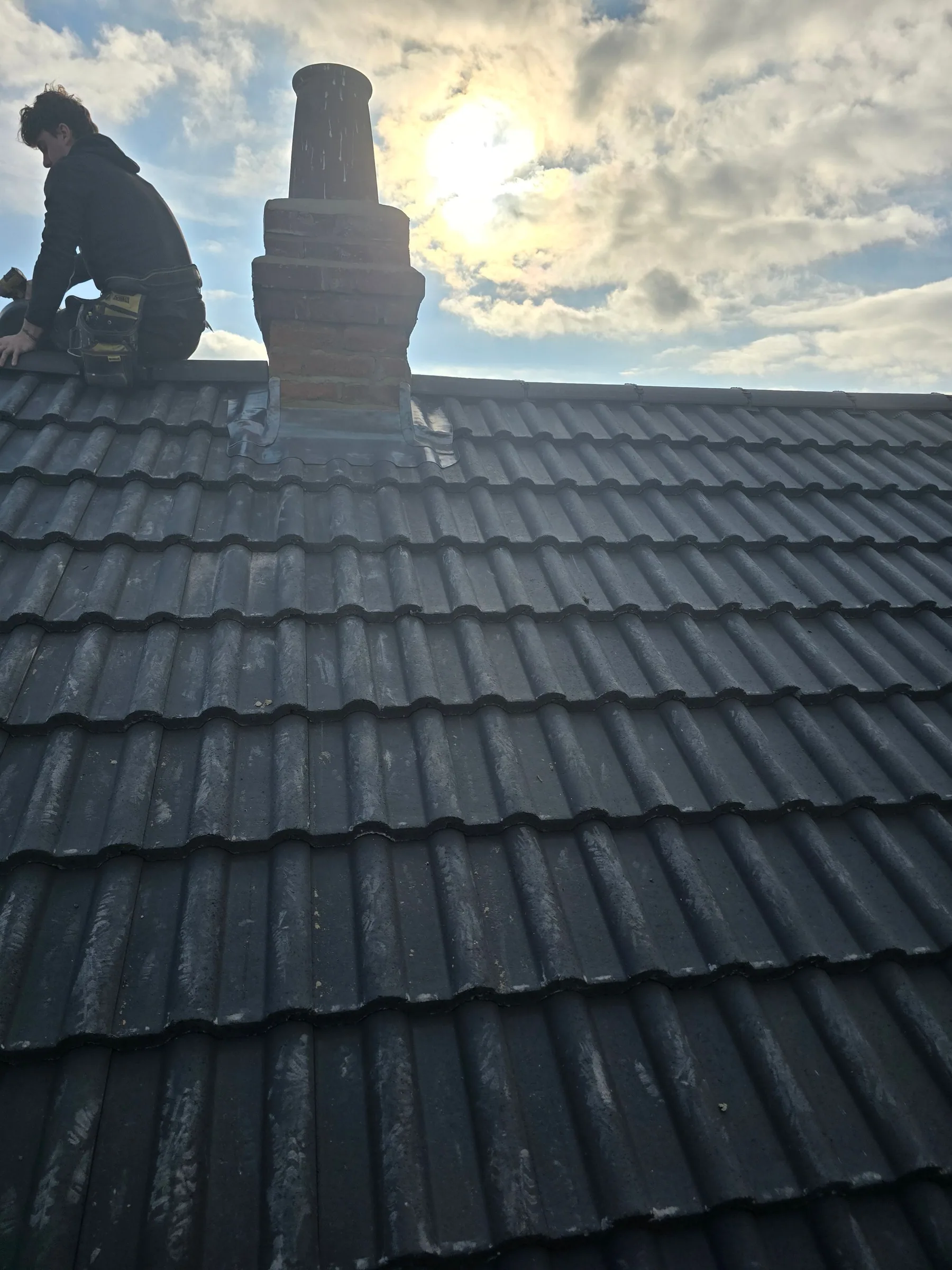 BHR roofer working beside a chimney on a tiled roof